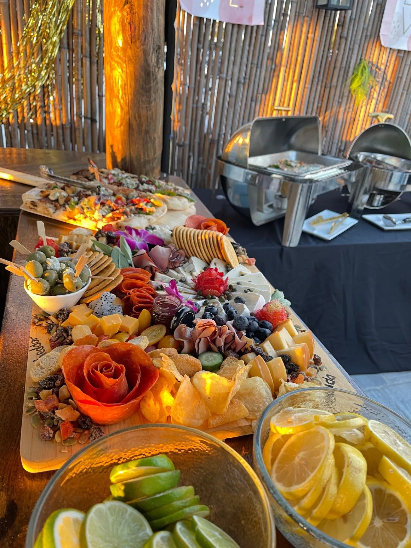 Catering buffet with a charcuterie board, fruit, and chilled lemon and lime slices
