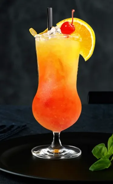 Colorful tropical cocktail in a hurricane glass with orange, cherry, mint, and a straw