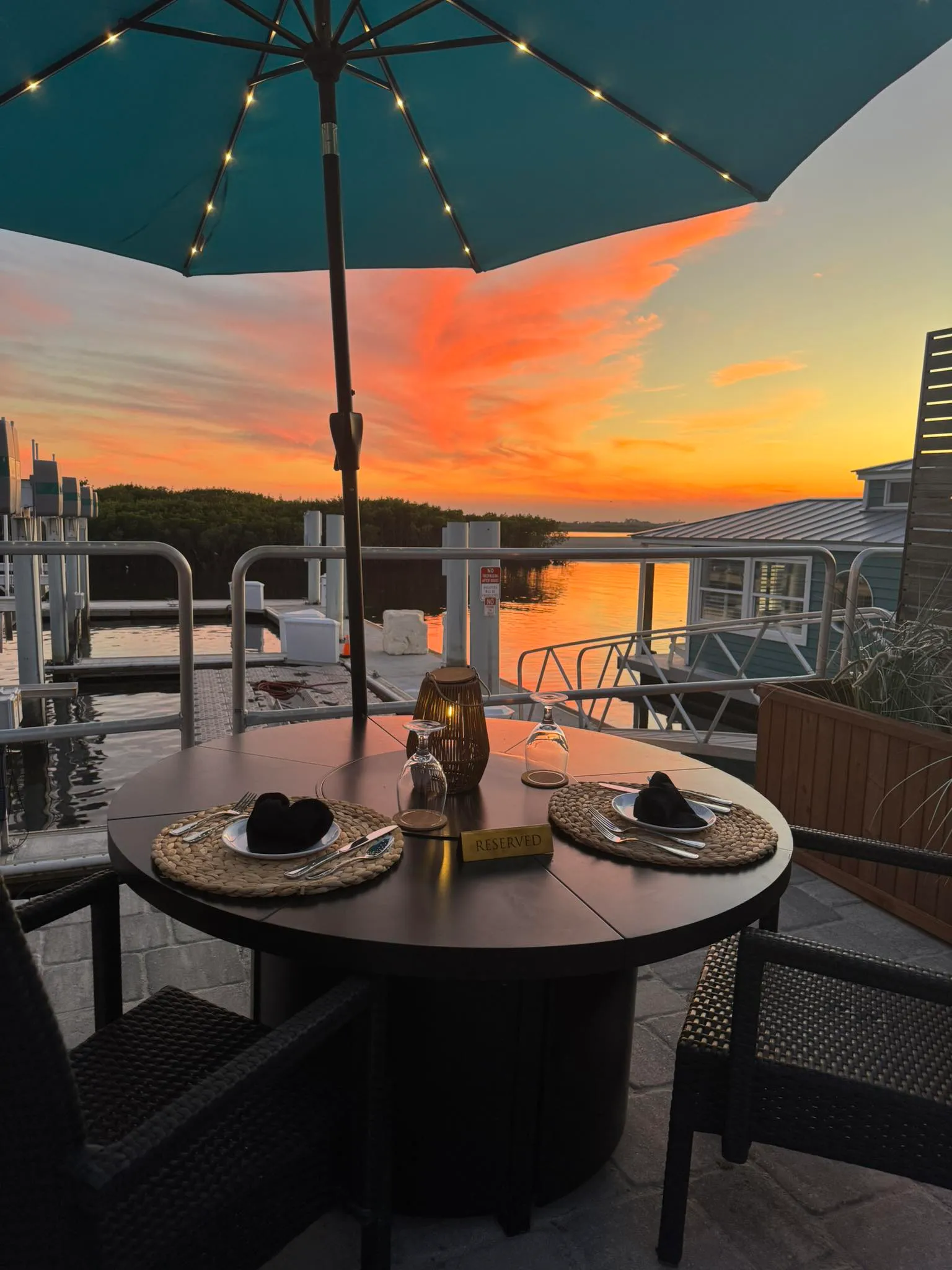 Waterfront patio seating at HT's Sand Bar & Bistro beneath blue umbrellas
